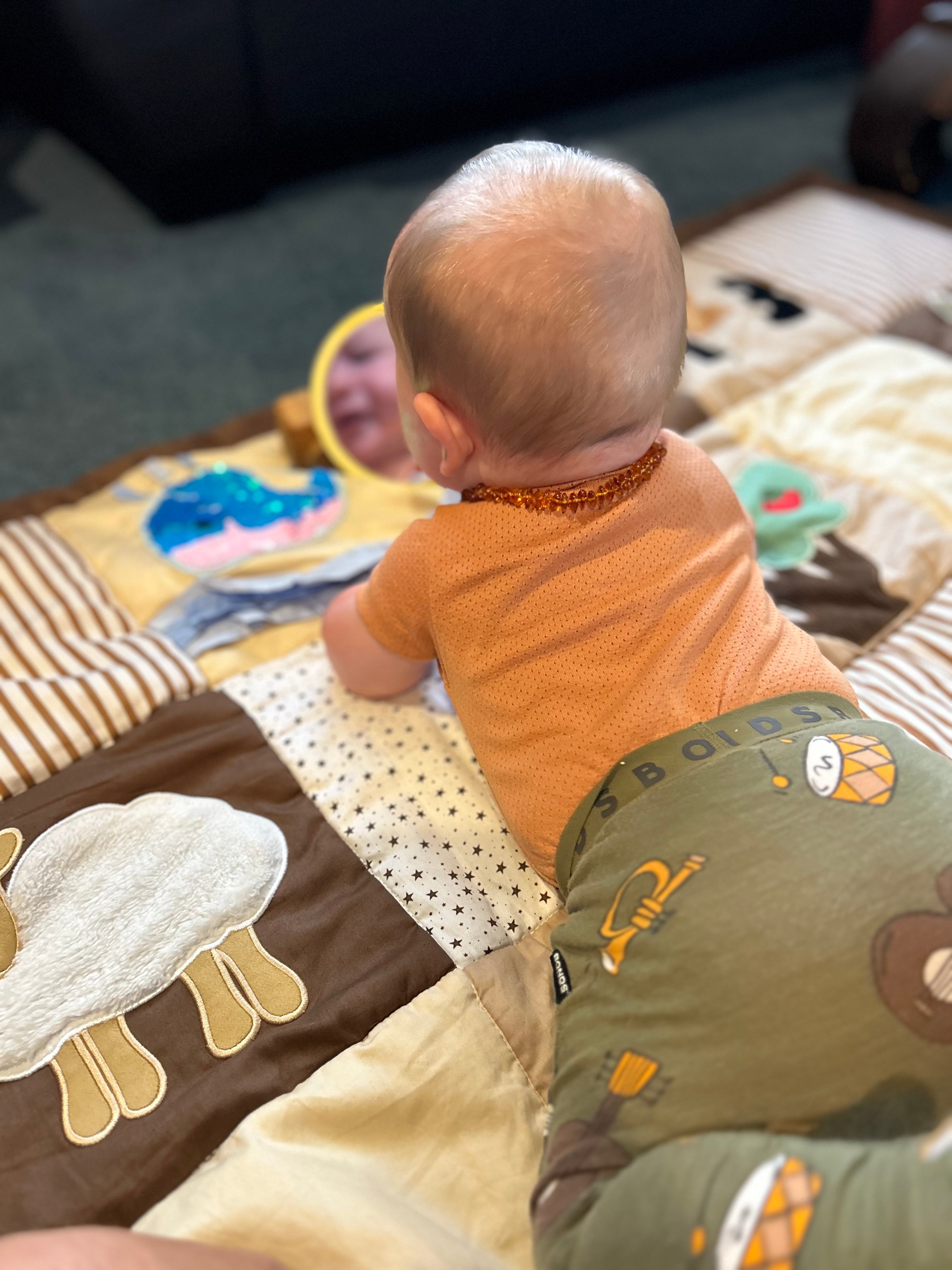 Baby looking in mirror on sensory play mat