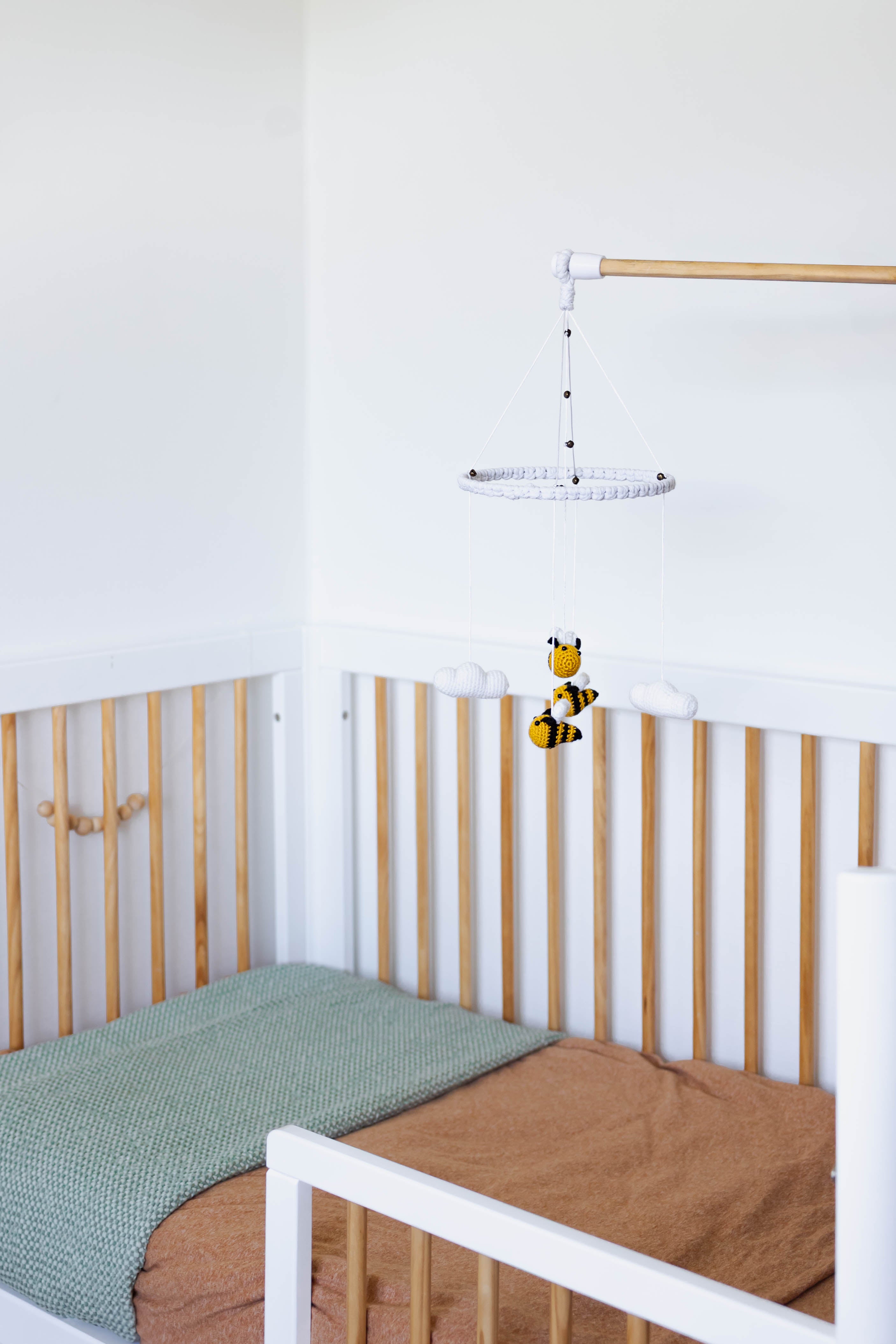 White bee baby mobile hanging over cot/crib