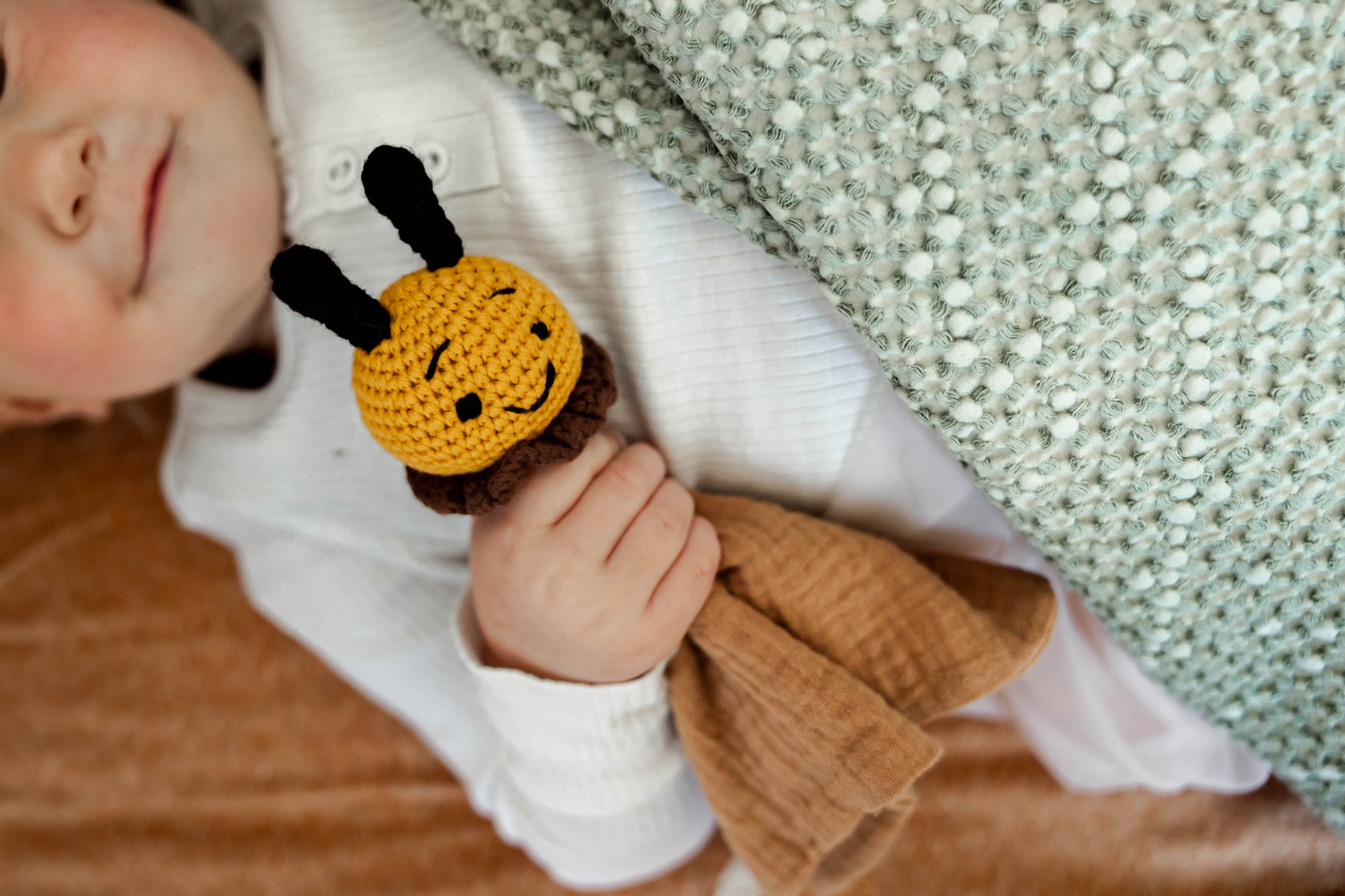 baby hands holding a bee comforter with brown material