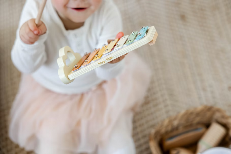 child playing a rainbow coloured xylophone