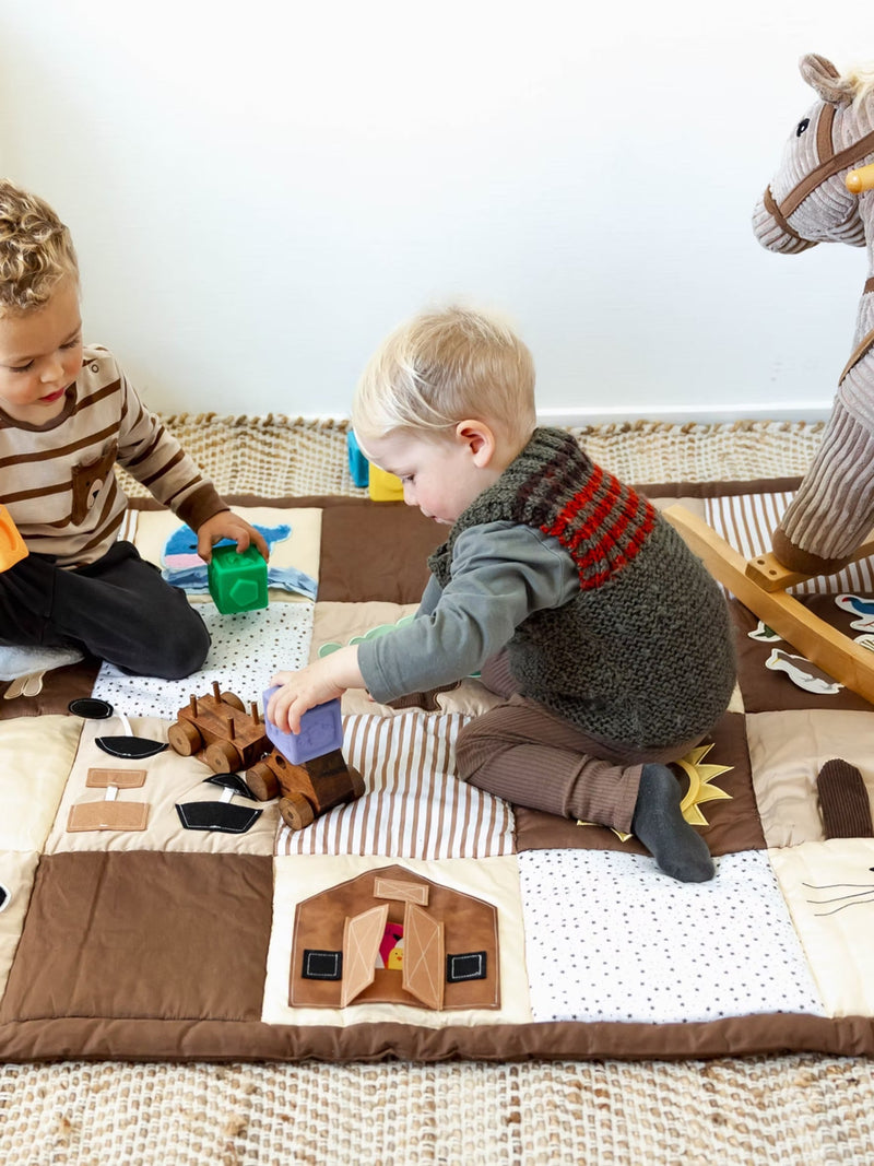 Two children playing with some toys on a play mat