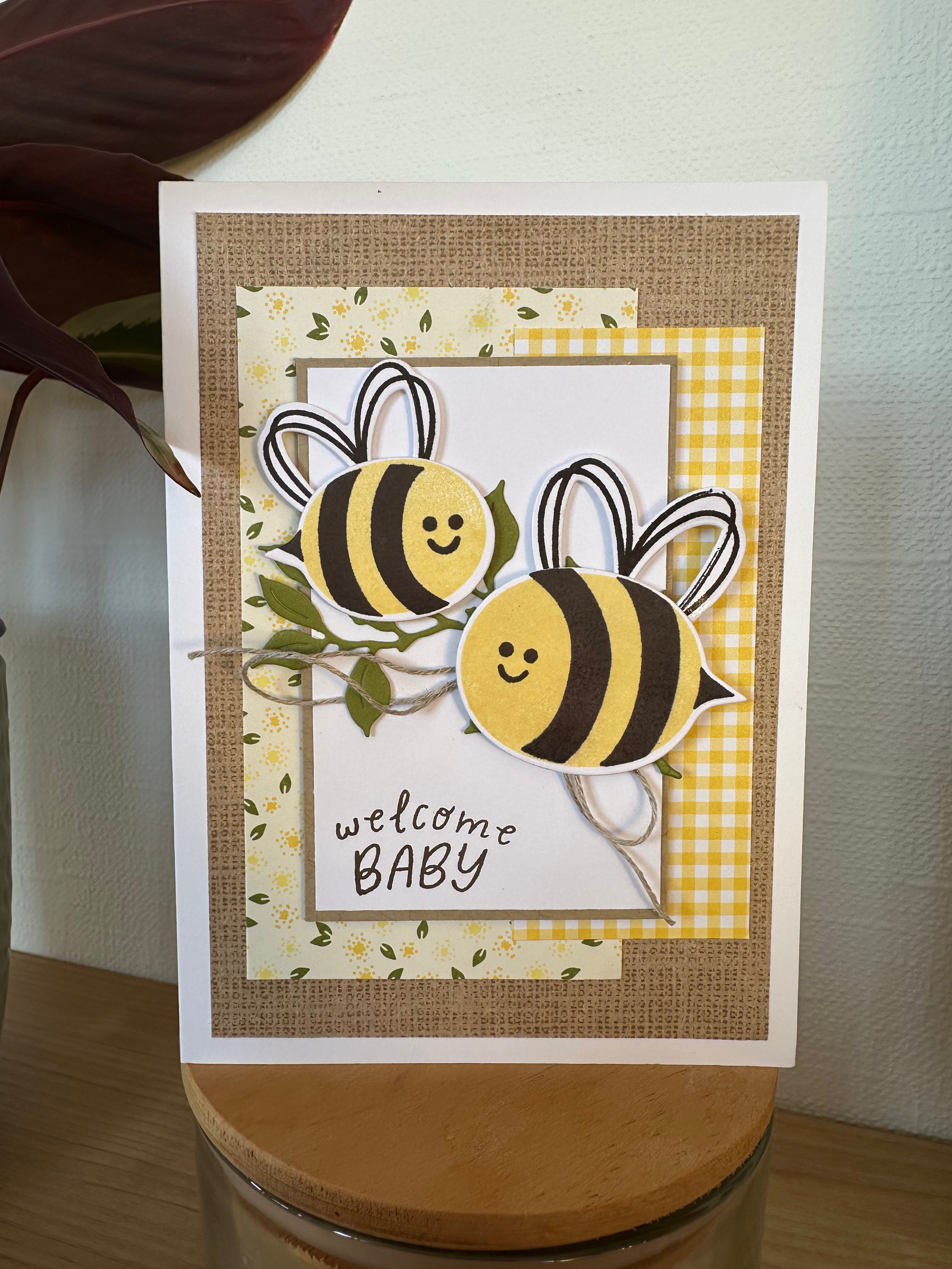 Baby shower card with bee design and 'welcome baby' text on a textured background
