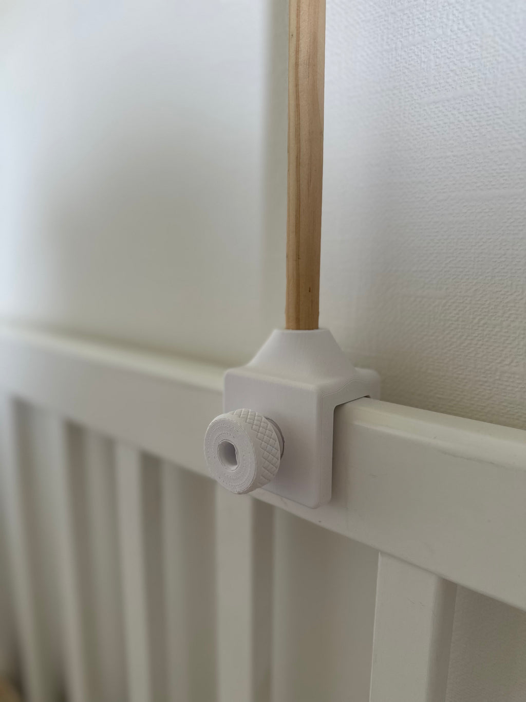 Close-up of a white 3D printed with a wooden rod against a white wall.