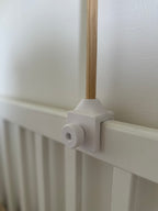 Close-up of a white 3D printed with a wooden rod against a white wall.