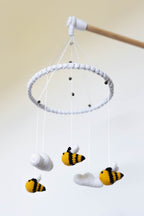 Crocheted baby mobile with bees and clouds on a white background