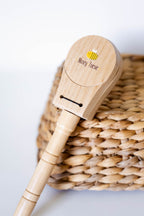Wooden clapper instrument toy with 'Nosey Toesie' branding on a woven basket background