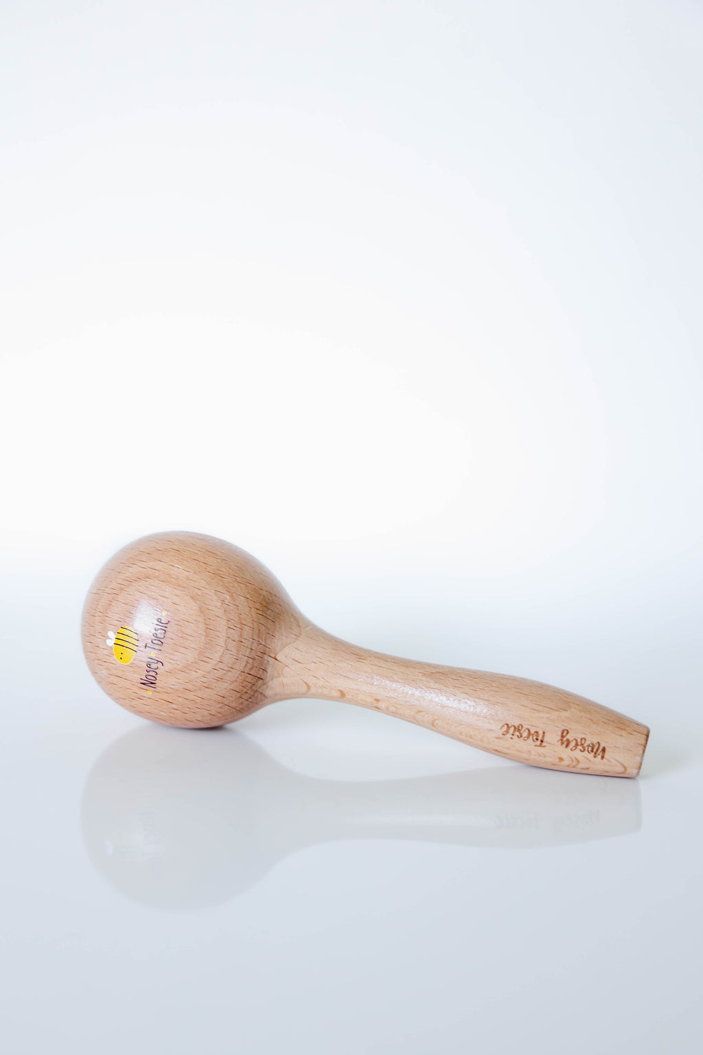 Wooden marraca with a visible brand logo 'Nosey Toesie' on a white background