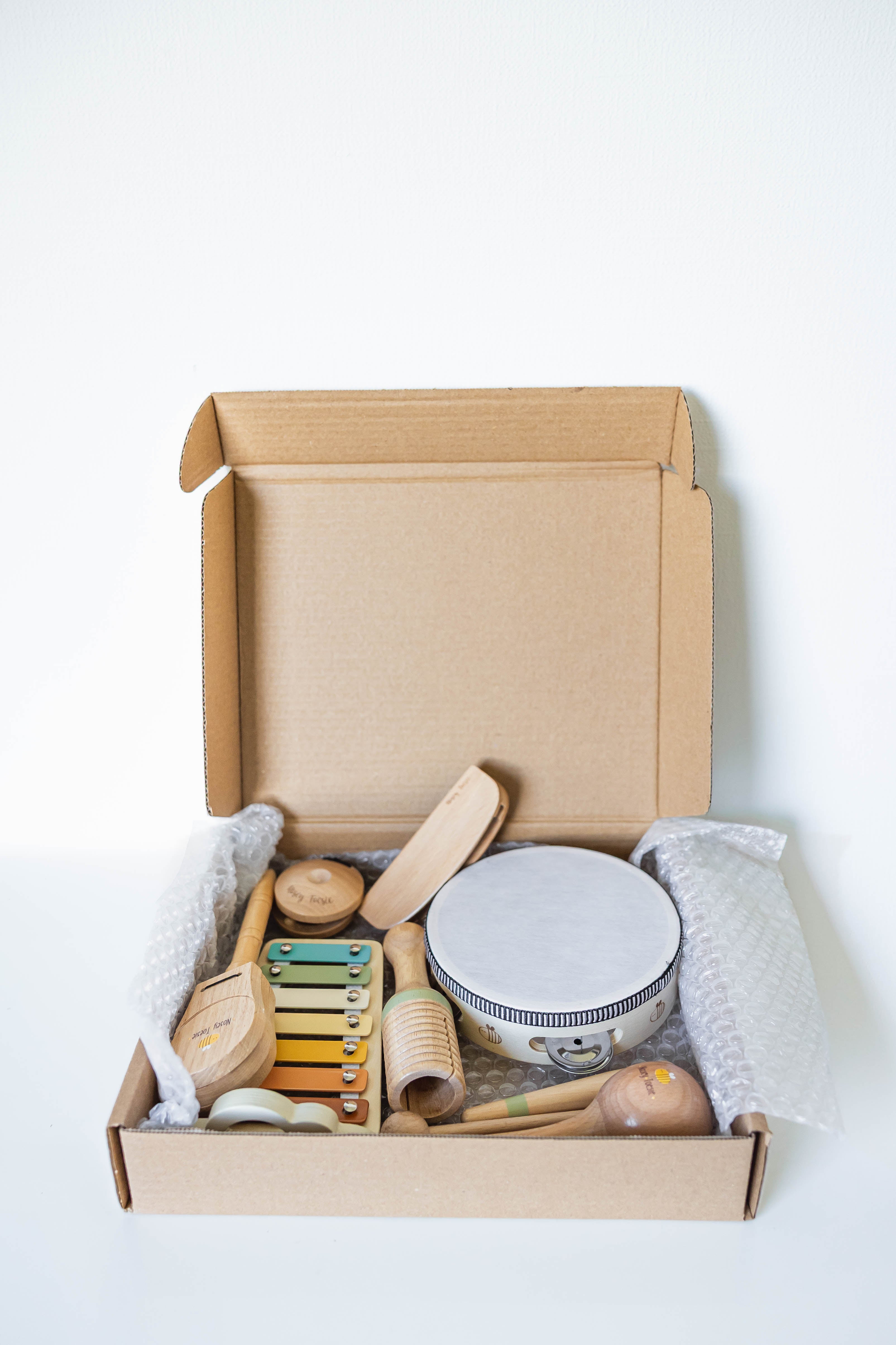 Open cardboard box containing musical instruments on a white background