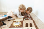 Two children playing on a patterned play mat indoors