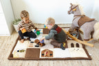 Two children playing with toys on a baby play mat in a room with a rocking horse.