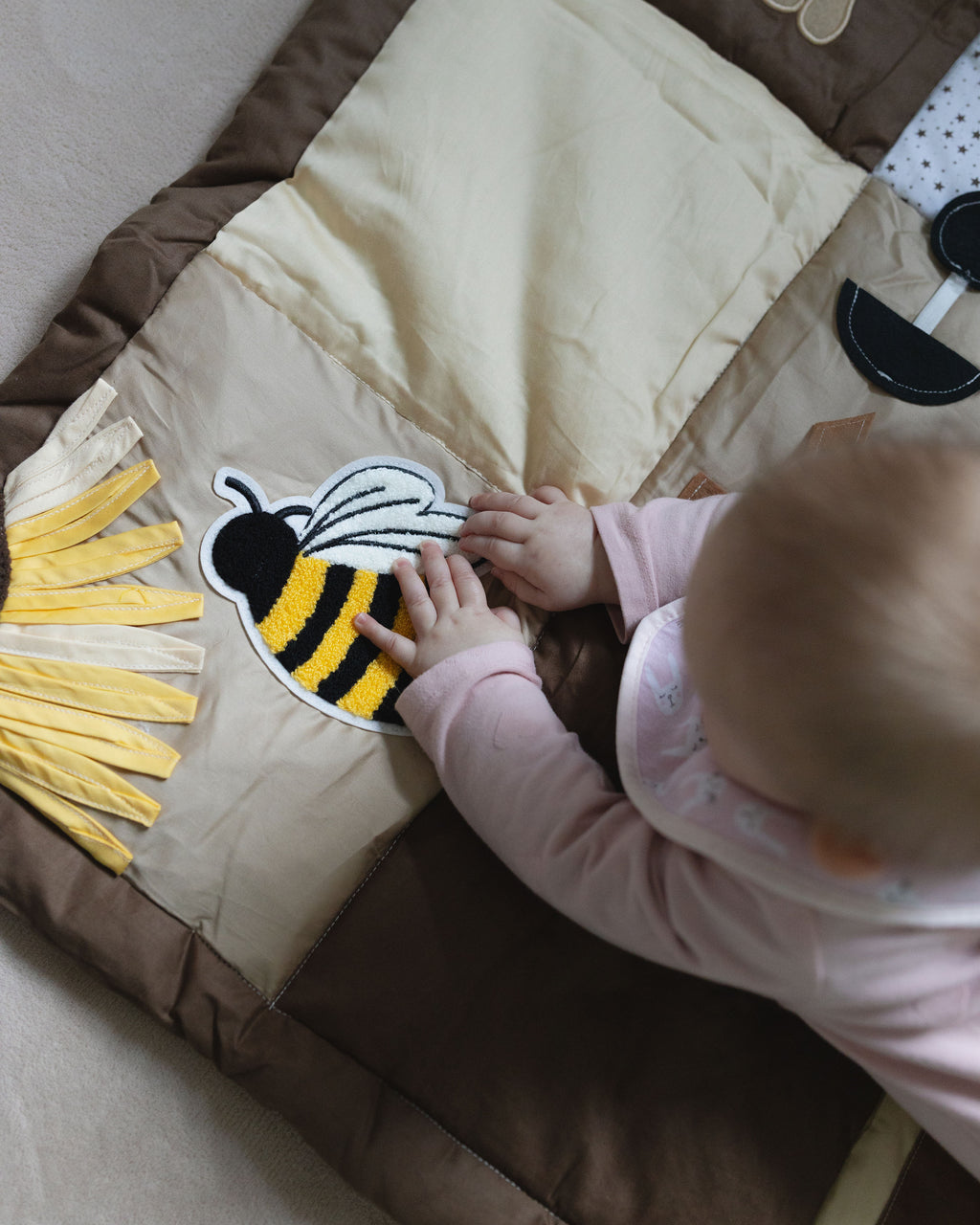 Baby playing with a bee on a brown play mat