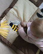 Baby playing with a bee and sunflower on a brown play mat