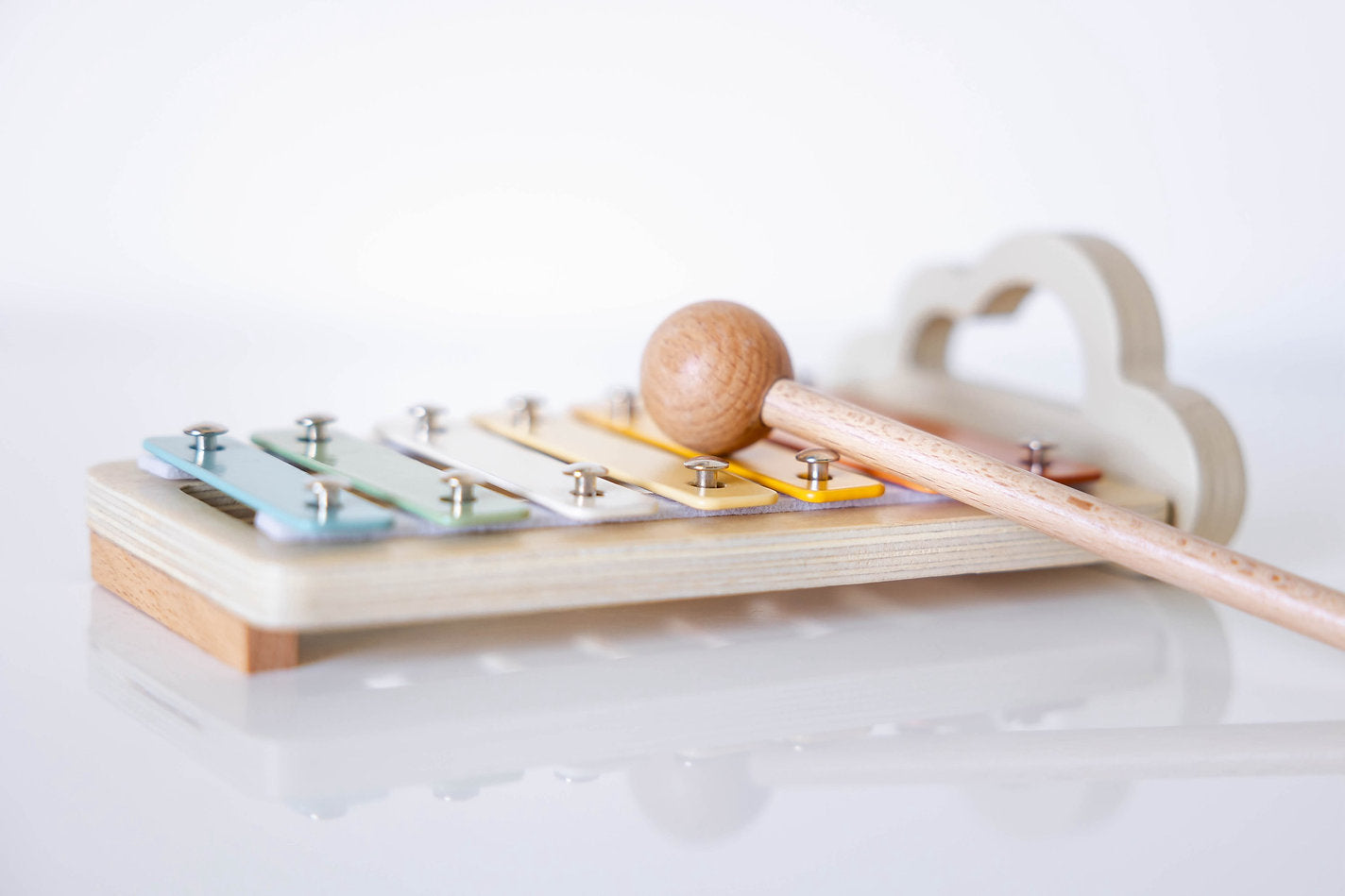 Wooden xylophone with metal keys and wooden mallet on a white background