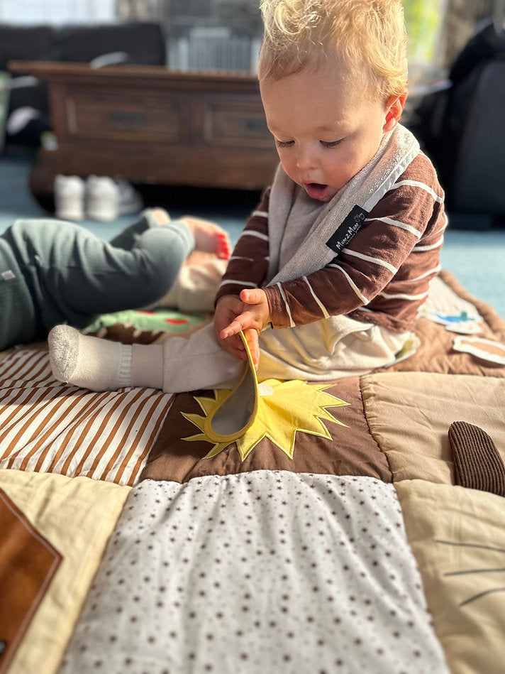 Child playing with a mirror on a baby play mat